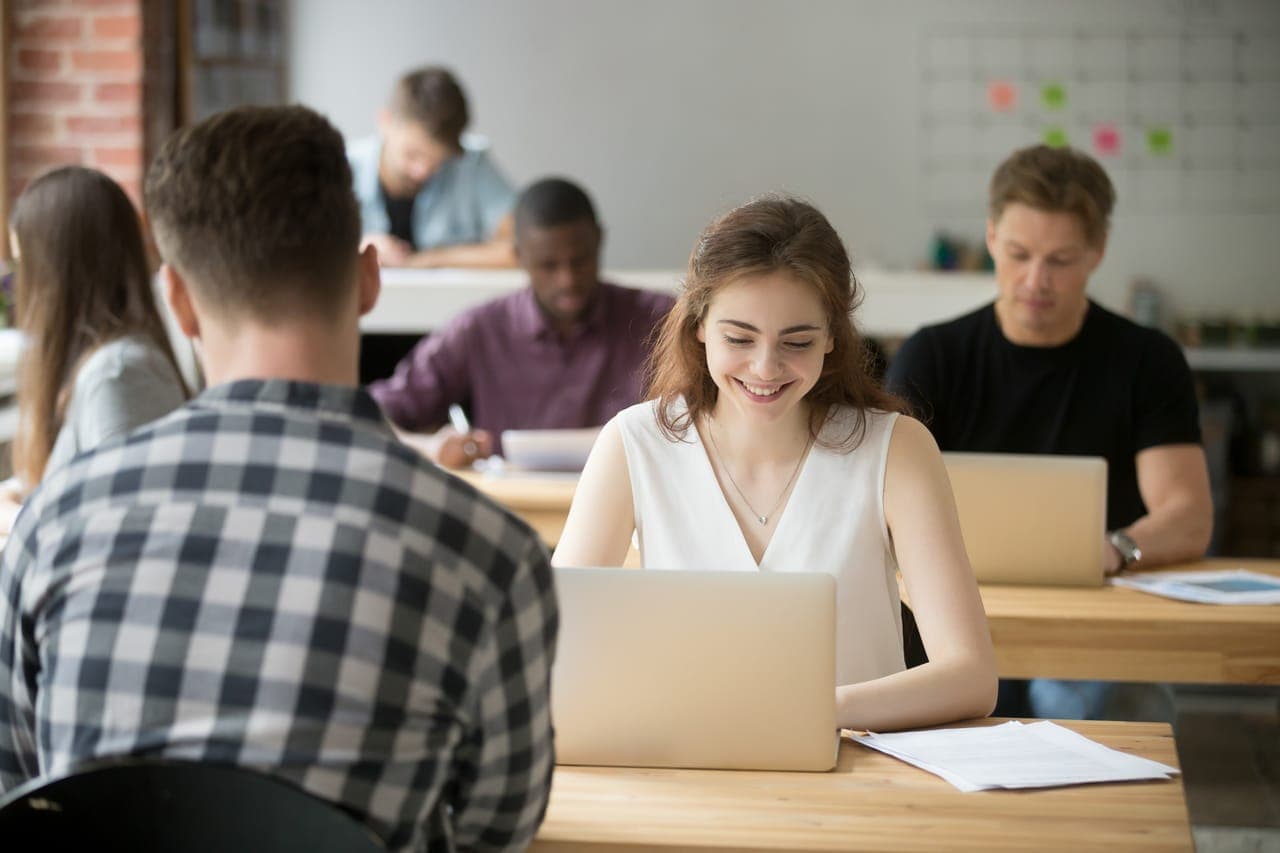 Young smiling woman working on laptop in coworking office space