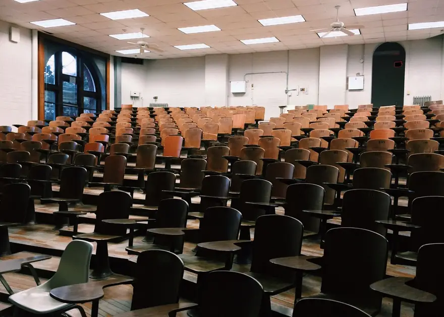 University lecture hall with wooden chairs and large windows