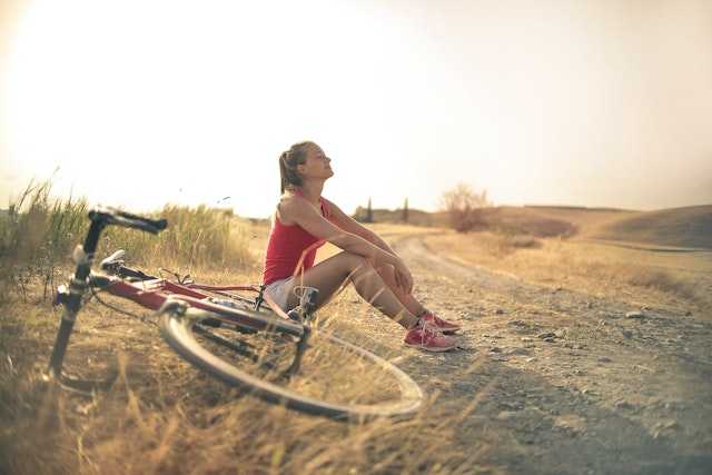 Woman sitting on the road next to a bicycle