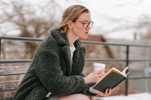 Woman sitting on a bench with a book and coffee